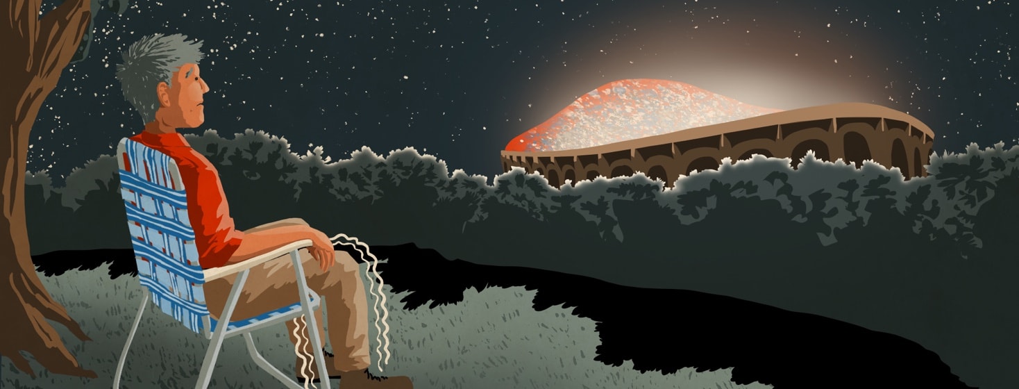 Man with dyskinesia sitting watching a stadium with an event going on from afar
