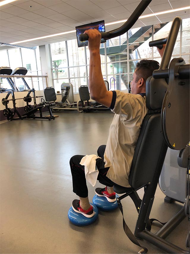 A man uses a weight machine to exercise his upper body.