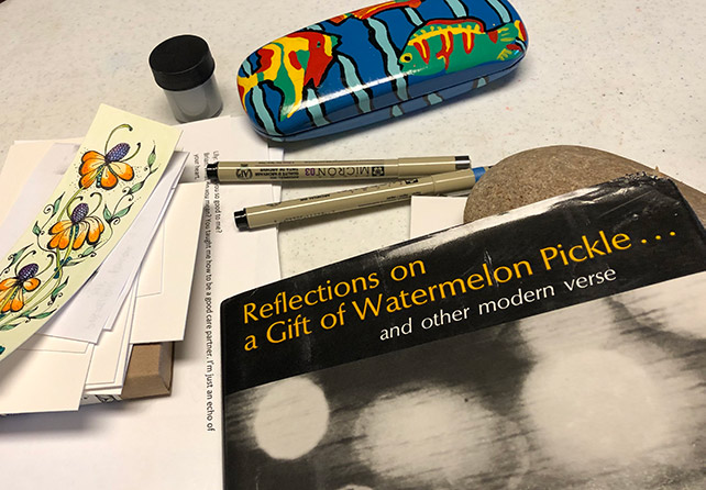 Art pens, paper, and a book titled Reflection on a Gift of Watermelon Pickle.