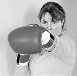 Portrait photo of adult woman with an intense expression wearing boxing gloves.