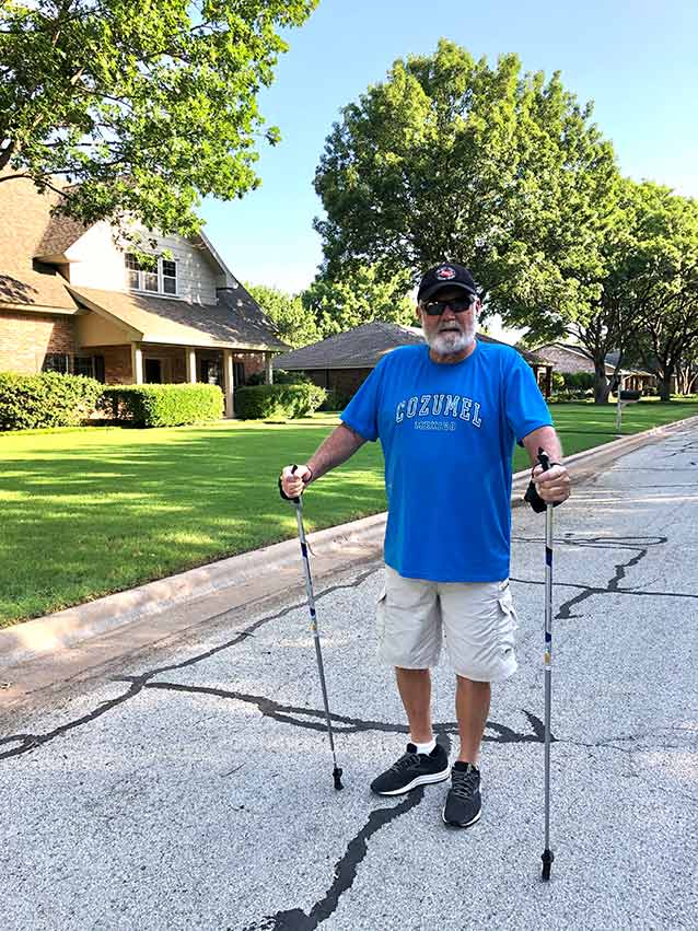 Man walking down a residential street with walking poles.