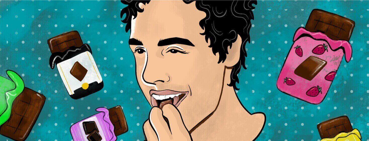 A man smiles as he puts a piece of chocolate in his mouth
