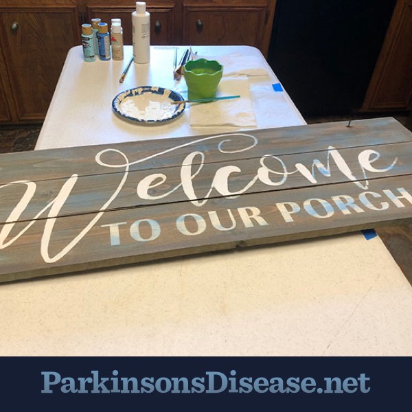 Painting supplies and a wooden sign reading Welcome to our Porch.